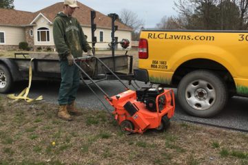 A man pushing an orange lawn mower