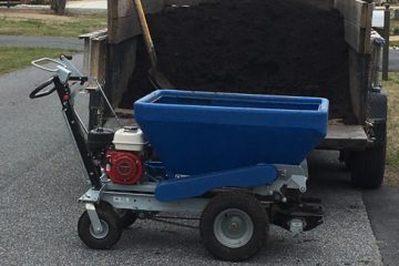 A blue mulching and fertilization spreader being filled with mulch
